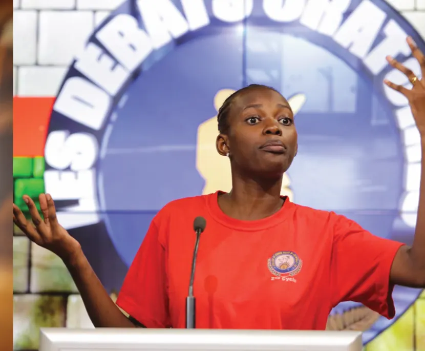 Oratrice s'exprimant au pupitre devant le logo des Débats Oratoires